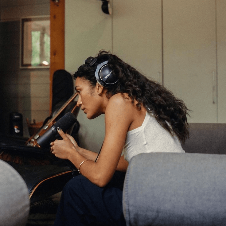 Cantora com auscultadores a gravar ao microfone no estúdio