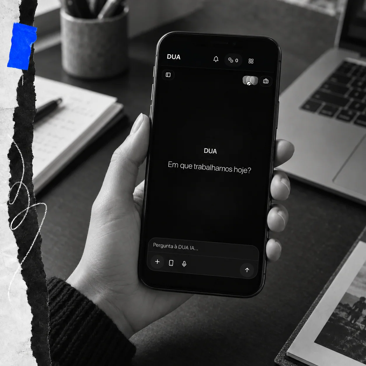Telemóvel com a interface do Chat DUA numa mesa de trabalho criativa